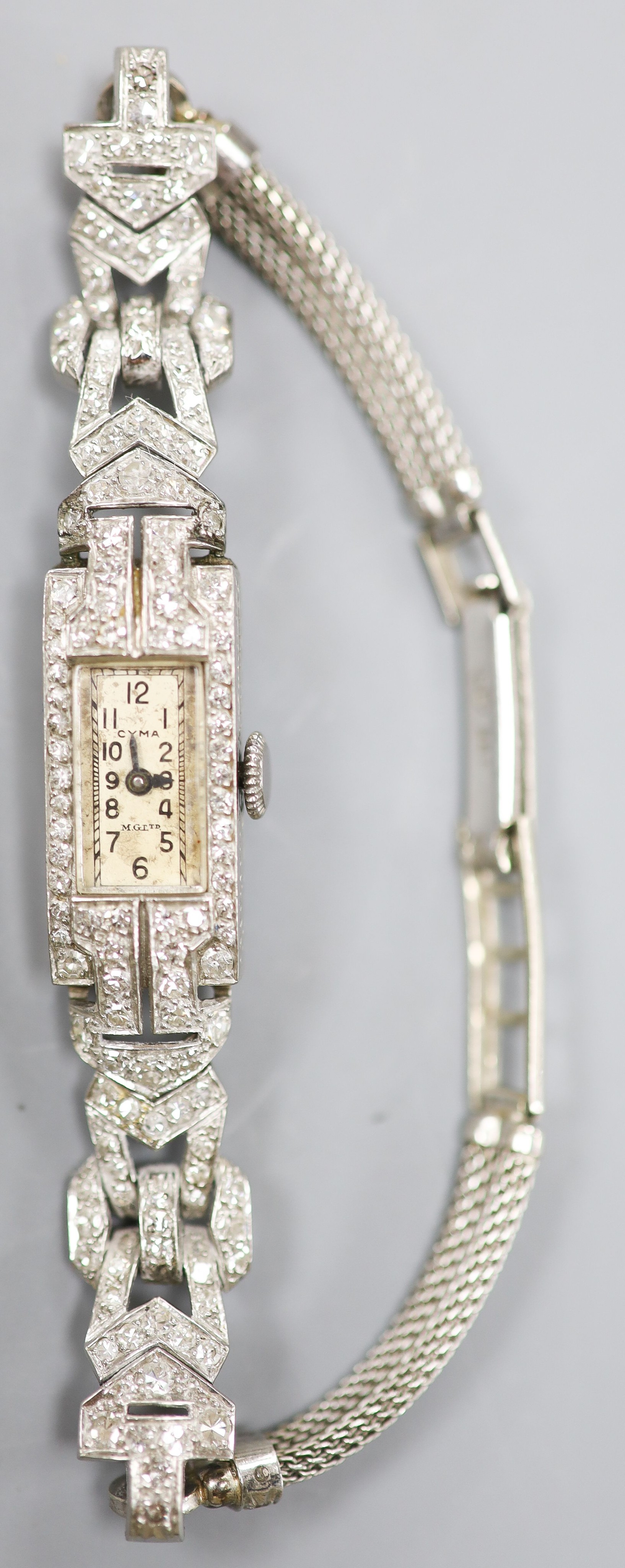 A white metal (stamped All platinum) and diamond set manual wind cocktail watch, on a 9ct white metal mesh bracelet, gross weight 21.6 grams.